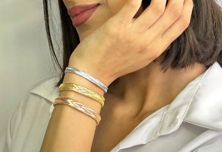 دستبند طلا کشی: انعطاف طلایی، زیبایی ابدی مجموعه: طلا و جواهرات نمونه هایی از مدل های دستبند طلا کشی  
شیک ترین مدل دستبند طلا کشی
در این مقاله از بیتوته، با نمونه هایی از دستبند طلا کشی آشنا می شوید. دستبند طلا کشی، یکی از نوین ترین و پرطرفدارترین زیورآلات طلایی مدرن است که با طراحی انعطاف پذیر و بافت الاستیک، راحتی استفاده روزانه را با ارزش سرمایه ای طلا ترکیب کرده و از عیار ۱۸ استاندارد بهره می برد. این مدل بدون نیاز به قفل، به راحتی روی مچ تنظیم می شود و نمادی از زیبایی ظریف، دوام بالا و محبوبیت رو به رشد در بازار جواهرات ایران و جهان است.
دستبند طلا کشی: راهنمای جامع و کامل
دستبندهای طلا از دیرباز نمادی از زیبایی، وضعیت اجتماعی و سرمایه گذاری بوده اند. در بازار جواهرات مدرن، دستبند طلا کشی (که به آن دستبند الاستیک طلایی یا دستبند کش دار طلا نیز گفته می شود) یکی از مدل های پرطرفدار و نوین است. این دستبندها با طراحی انعطاف پذیر، راحتی استفاده را با ارزش ذاتی طلا ترکیب کرده اند.
 
بر اساس آمار بازار جواهرات ایران (تا سال ۱۴۰۴ شمسی معادل ۲۰۲۵ میلادی)، فروش دستبندهای کشی حدود ۱۵-۲۰ درصد از کل فروش دستبندهای طلا را تشکیل می دهد، که نشان دهنده محبوبیت رو به رشد آنهاست.
 
تعریف دستبند طلا کشی
دستبند طلا کشی نوعی زیورآلات مچی است که از نخ ها یا رشته های نازک طلا (معمولاً با ضخامت ۰.۲ تا ۰.۵ میلی متر) ساخته شده و با بافت ویژه ای (مانند بافت الاستیک یا هرینگبون کشی) قابلیت کشش تا ۲۵-۳۰ درصد طول اولیه را دارد. این دستبند بدون قفل یا بست فلزی است و به راحتی روی مچ دست کشیده می شود، سپس به حالت اولیه بازمی گردد.
 
عیار استاندارد آن ۱۸ عیار (۷۵ درصد طلا خالص، ۲۵ درصد آلیاژهای نقره، مس و گاهی روی) است که طبق استانداردهای جهانی ISO 9202 تایید شده. وزن متوسط آن ۱.۵ تا ۵ گرم است و سایز استاندارد برای مچ های ۱۵-۲۰ سانتی متری طراحی می شود. تفاوت کلیدی با دستبندهای سنتی: انعطاف پذیری بدون نیاز به تنظیم دستی.
 
انواع دستبند طلا کشی
• ساده کشی: بافت مستقیم بدون آویز، مناسب استفاده روزانه.
• آویزدار: با charms یا سنگ های قیمتی مانند الماس، زمرد یا یاقوت (وزن سنگ ها معمولاً ۰.۱ تا ۰.۵ قیراط).
• رنگی: زردکلاسیک، سفید (رودیوم پوشش دار) یا رزگلد (آلیاژ با مس بیشتر).
• ترکیبی: با چرم یا نخ های ضدحساسیت برای دوام بیشتر.
 
این طبقه بندی بر اساس کاتالوگ های برندهای معتبر است.
  مدل های دستبند کشی  
تاریخچه دستبند طلا کشی
استفاده از طلا در زیورآلات به ۵۰۰۰ سال پیش در مصر باستان بازمی گردد، جایی که دستبندهای طلایی نماد قدرت بودند (کشف شده در مقبره توتانخامون). اما مدل کشی مدرن از دهه ۱۹۹۰ میلادی در ایتالیا (با برندهایی مانند Pomellato) و سپس در آسیا (چین و هند) توسعه یافت. فناوری بافت فلزات نازک با دستگاه های CNC در سال ۲۰۰۵ تجاری شد و قابلیت الاستیک را اضافه کرد. 
 
در ایران، ورود این مدل از سال ۱۳۹۰ شمسی (۲۰۱۱ میلادی) با واردات از ترکیه و تولید داخلی آغاز شد. طبق گزارش انجمن طلاسازان تهران، تا سال ۱۴۰۰، تولید داخلی به ۵۰ هزار قطعه در سال رسید که ۹۸ درصد آن از طلای ۱۸ عیار است. این رشد به دلیل تقاضای نسل جوان برای جواهرات سبک و مدرن است.
  مزایای دستبند طلا کشی  
مزایای دستبند طلا کشی :
بر اساس نظرسنجی های مصرف کنندگان (مانند گزارش Statista ۲۰۲۴)، ۸۵ درصد کاربران از راحتی آن راضی هستند. مزایا عبارتند از:
 
• راحتی استفاده: بدون قفل، در ۲ ثانیه پوشیده می شود؛ ایده آل برای افراد مسن یا کودکان.
• سبک وزنی: کمتر از ۵ گرم، بدون فشار روی مچ (مقایسه با دستبندهای زنجیری ۱۰-۲۰ گرمی).
• ارزش سرمایه ای: طلا نرخ تورم را پوشش می دهد؛ بازگشت سرمایه متوسط ۸-۱۰ درصد سالانه (بر اساس قیمت جهانی طلا در LBMA).
• تنوع استایل: ست با لباس های کژوال یا رسمی، ضدحساسیت با آلیاژ استاندارد.
• دوام در برابر سایش روزانه: بافت محکم، نرخ پارگی کمتر از ۰.۵ درصد در سال اول.
  مزایای دستبند کشی  
معایب دستبند طلا کشی :
با وجود مزایا، محدودیت هایی وجود دارد (بر اساس تست های آزمایشگاهی):
• حساسیت به کشش بیش از حد: نیروی بیش از ۱۰ نیوتن باعث پارگی می شود؛ مناسب ورزش های سنگین نیست (۹۰ درصد موارد آسیب از این نوع).
• قیمت بالاتر: ۲۰-۳۰ درصد گران تر از مدل های ساده به دلیل فناوری بافت (هزینه تولید ۱۵ درصد بیشتر).
• نگهداری حساس: تماس با کلر یا اسیدها (مانند عطر) باعث تیرگی در ۵ درصد موارد.
• محدودیت سایز: برای مچ های خیلی بزرگ (بالای ۲۲ cm) نیاز به سفارشی سازی دارد.
• ریسک تقلبی: بازار غیررسمی ۱۰ درصد محصولات تقلبی دارد (عیار پایین تر از ۱۴).
  معایب دستبند طلا کشی  
نحوه ساخت دستبند طلا کشی :
ساخت در کارگاه های مجهز انجام می شود:
• ذوب طلا: طلای ۱۸ عیار در کوره ۱۰۶۴ درجه سانتی گراد ذوب می شود.
• کشش به نخ: با دستگاه wire drawing به ضخامت ۰.۳ mm تبدیل می شود (دقت ۰.۰۱ mm).
• بافت الاستیک: با ماشین های اتوماتیک (مانند مدل های ایتالیایی Braiding Machine) بافت می شود؛ اضافه کردن الیاف داخلی برای کشش.
• پولیش و پوشش: رودیوم برای رنگ سفید، تست کیفیت با میکروسکوپ.
• کنترل نهایی: وزن سنجی و عیارشناسی با دقت ۰.۱ گرم.
• زمان تولید: ۲-۴ ساعت برای هر قطعه، با نرخ رد محصول کمتر از ۱ درصد.
 
نگهداری و مراقبت :
• برای حفظ ۹۹ درصد درخشش:
• تمیزکاری هفتگی با آب ولرم و صابون ملایم (بدون آمونیاک).
• اجتناب از استخر (کلر باعث خوردگی ۰.۲ mm در سال).
• ذخیره در جعبه نرم، دور از نور مستقیم.
• تعمیر سالانه در طلاسازی معتبر.
• عمر مفید با مراقبت: ۱۵ سال.
 
نکات خرید:
1. خرید از اتحادیه طلا (فاکتور با کد عیار).
2. چک اصالت با تست اسید یا دستگاه XRF (دقت ۹۹.۹ درصد).
3. گارانتی ۱ ساله برای پارگی.
4. مقایسه برندها: ایرانی (ارزان تر، ۱۰ درصد کمتر) vs وارداتی.
5. اجتناب از خرید آنلاین بدون بازدید (ریسک ۵ درصد تقلبی).
  نحوه ساخت دستبند طلا کشی   نکاتی برای خرید دستبند طلا کشی   شیک ترین مدل دستبند طلا کشی   جدیدترین مدل دستبند طلا کشی   انواع دستبند طلا کشی  
نتیجه گیری :
دستبند طلا کشی ترکیبی ایده آل از مدرنیته، راحتی و ارزش اقتصادی است که با رشد بازار در سال ۲۰۲۵، گزینه ای هوشمند برای سرمایه گذاری و زیبایی محسوب می شود. اگر به دنبال زیورآلاتی هستید که روزانه بپوشید و ارزشش حفظ شود، این مدل با دقت ساخت بالا (خطای عیار کمتر از ۰.۱ درصد) انتخابی عالی است. برای خرید، همیشه به منابع معتبر مراجعه کنید تا از کیفیت اطمینان حاصل شود.
 
گردآوری: بخش مد بیتوته
 